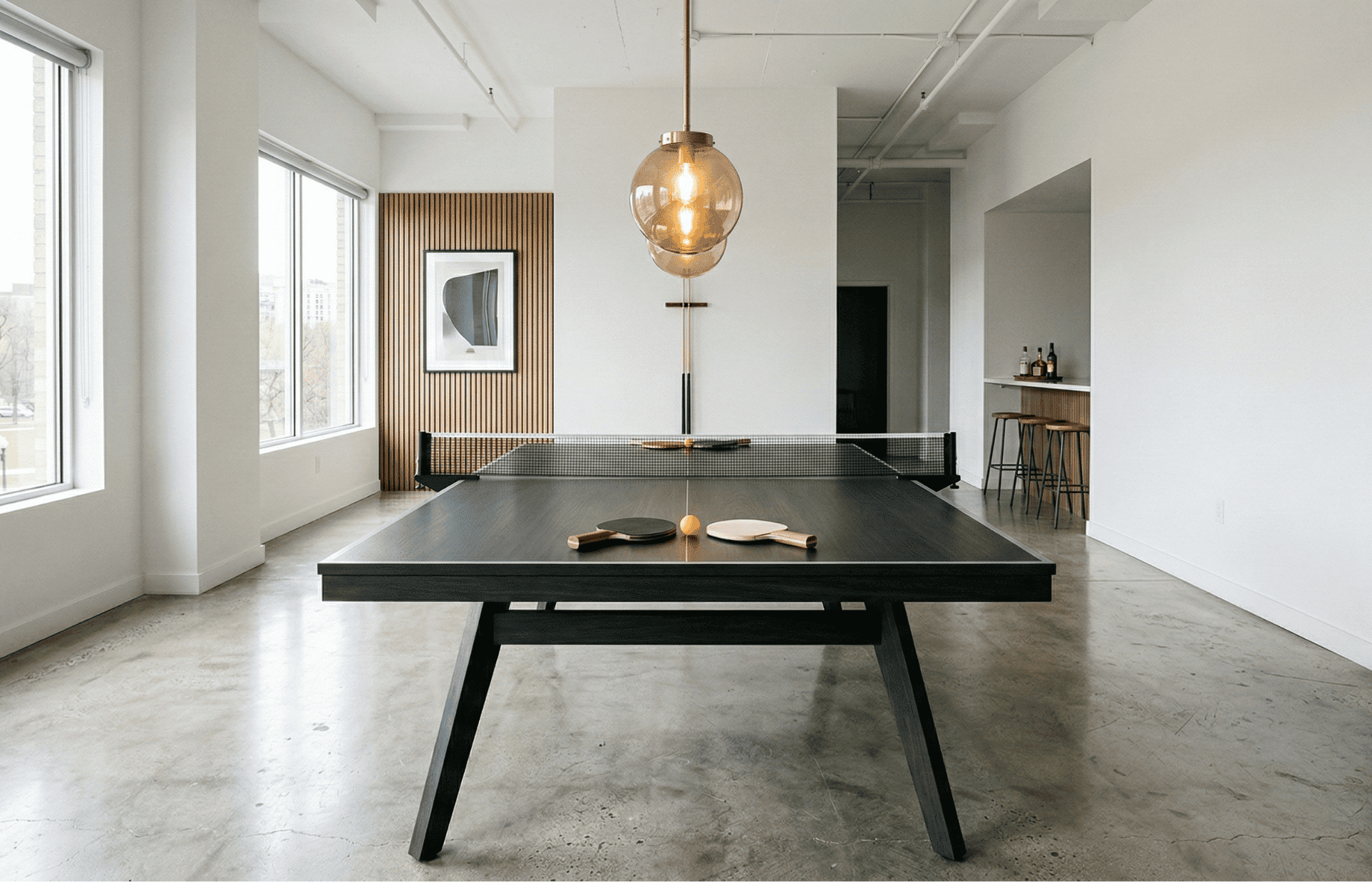 A bright modern game room with a premium dark-finish ping pong table in the center.