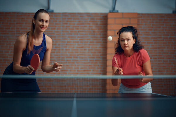 Women play doubles table tennis, ping pong players