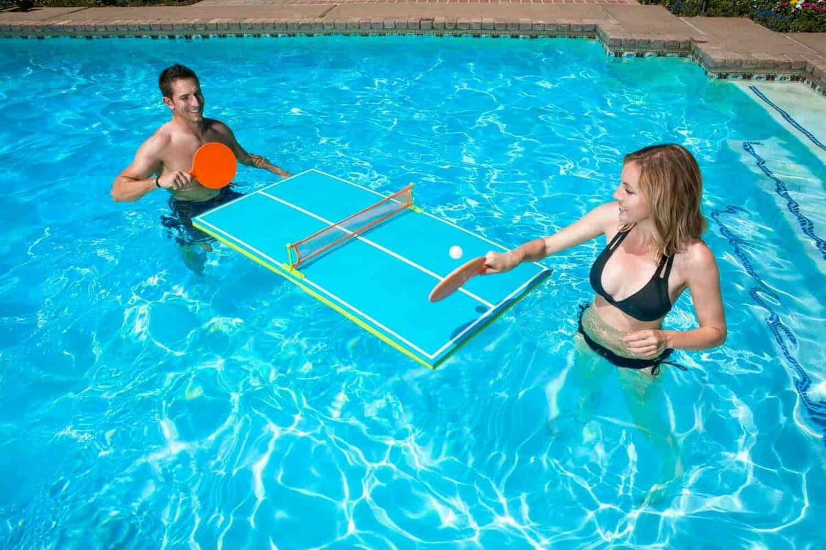 people playing ping pong on floating table in pool